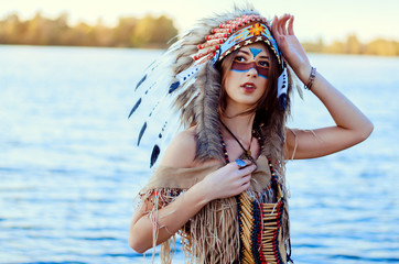 Portrait of a young woman in a traditional Indian costume and a rouce on her head, she stands in...