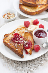 sweet breakfast - toasts with raspberries, banana and jam, vertical