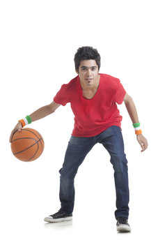 Full length portrait of young boy playing basketball over white background 