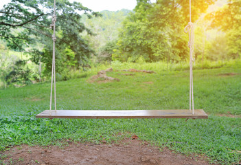 Fototapeta na wymiar wooden swing in garden with sunlight.