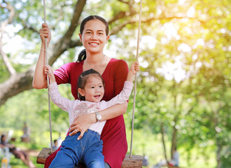 Smiling mother and her daughter lying on swinging in the garden.