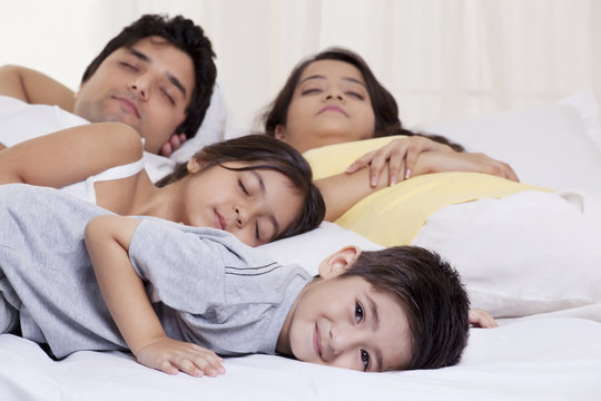 Portrait of boy smiling while his family sleeping in the background 