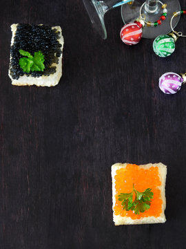 Canape with red and black caviar and wine glasses with Christmas decorations in the background