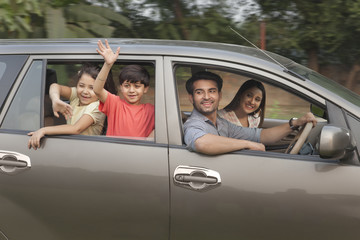 Children with parents waving from car window	
