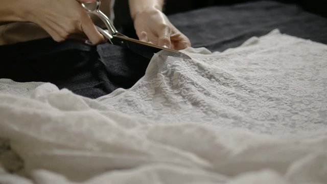  Seamstress cutting clothing fabric with a scissor