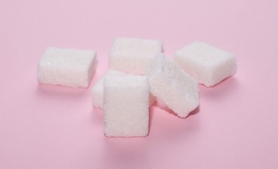 White sugar cubes isolated on pink background and texture
