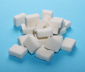 White sugar cubes isolated on blue background and texture