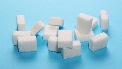 White sugar cubes isolated on blue background and texture