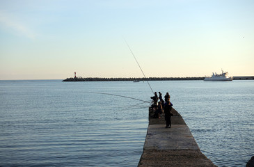 Fisherman fishes on a pier in the sea
