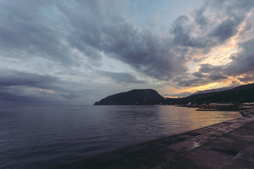 Sea. Mountains and the sea. Landscape background. Quaint clouds over the sea. Incredible sunset. Partly cloudy. Crimea. Summer. Evening scenery. Card with beautiful views.