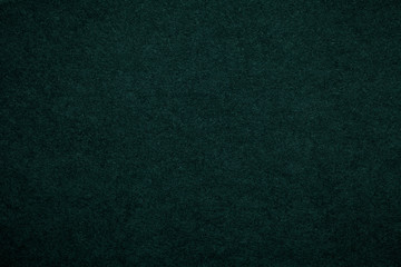 Texture of old dark green paper background, closeup. Structure of dense emerald cardboard