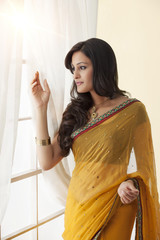 Side profile of a woman in a saree looking out a window