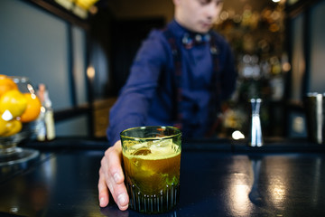 Bartender is making cocktail at bar.