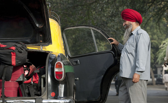 Sikh taxi driver holding the door of the vehicle open 