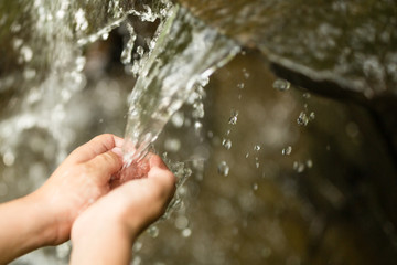 Water pouring in child hand on nature background.