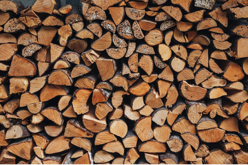 chopped logs for winter fire. Pile of firewood against old wooden fence