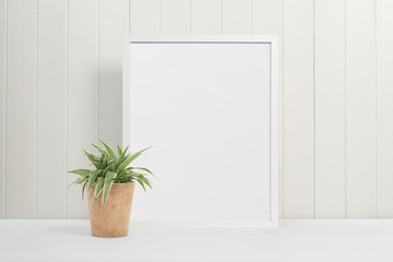 White picture frame on white background with plant pot