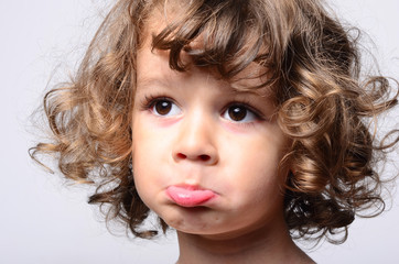 Portrait of a beautiful sad boy. Toddler feeling sadness because he was disappointed. Adorable boy having different emotions. Kid making funny faces. Boy with long curly hair. © iulianvalentin