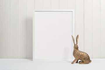 White picture frame on white background with gold rabbit