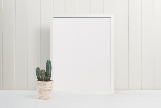 White picture frame on white background with cactus plant in plant pot