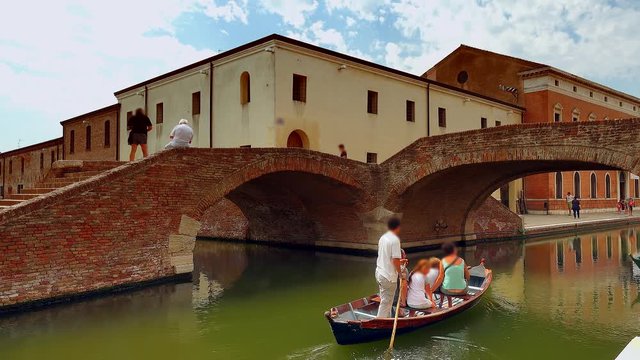 romantic holiday for tourists on Venetian gondola in canal passing  under bridges of lagoon city,  color graded clip