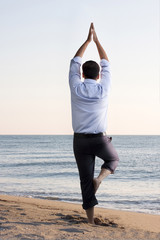 Fototapeta na wymiar Businessman doing yoga on the beach 