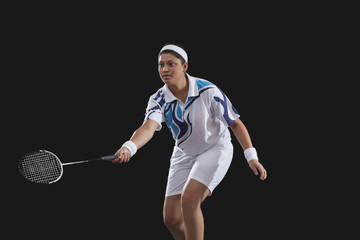 Young woman playing badminton over black background