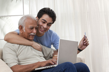 Fototapeta premium Grandson teaching grandfather how to operate laptop