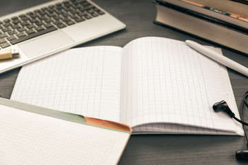 Office workplace with open laptop. Workspace of business man or student. notebooks, pen, books, earphones on grey wooden desk