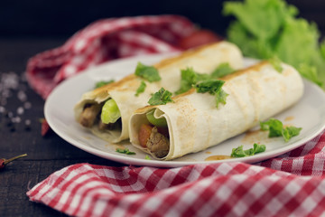 Lavash rolls with meat, vegetables and cheese served with green lettuce salad on rustic wooden table. Healthy breakfast concept. Greek traditional food - Gyro
