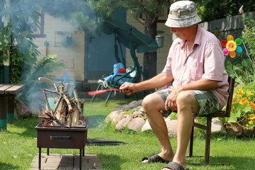 Grandpa lights the fire in the garden