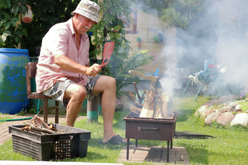 Senior man lights the fire in the garden
