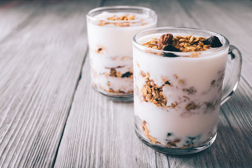 Yogurt with granola in cups on white table close-up