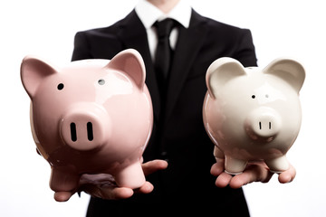 Businessman holding two piggy banks on a white background
