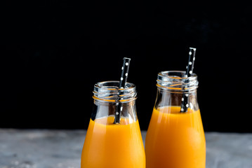 Two bottles of pumpkin juice with black straws Horizontal photo Close up