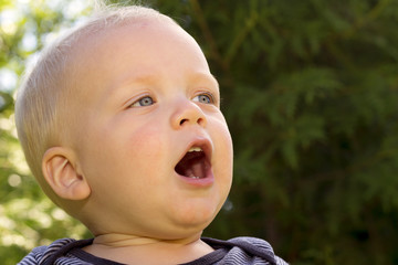 Close up portrait of funny blonde singing toddler. Outdoor shot