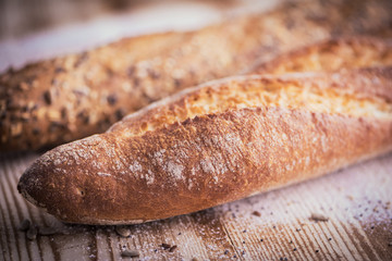 Closeup view of fresh crunchy baguette bread with sunflower seeds and other seeds on the rustic wooden desk