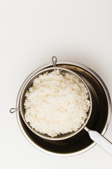Rice in sieve stainless steel bowl overhead.