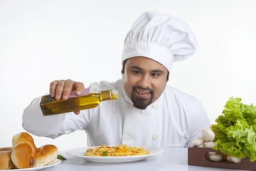 Chef pouring olive oil on pasta