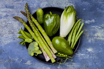 Green veggies group on a tray. Vegetarian dinner ingredients. Green vegetables variety. Overhead, flat lay, top view, copy space