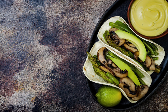 Grilled portobello, asparagus, bell peppers, green beans fajitas. Poblano mushroom tacos with jalapeno, cilantro, avocado crema. Vegan tacos with green summer vegetables. Copy space