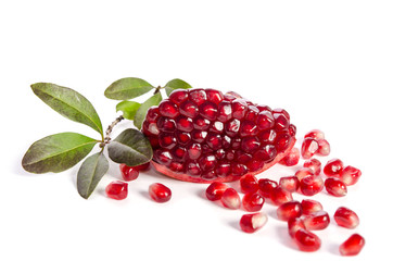 Part of a pomegranate with pomegranate seeds and leaves isolated on white background