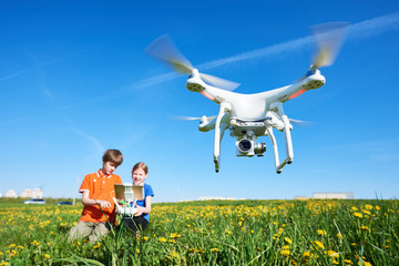 children operating of flying drone at sunset