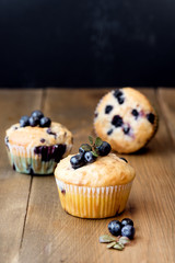 Muffin cupcakes with blueberries on a wooden background. Cupcakes decorated with berries Vertical photo
