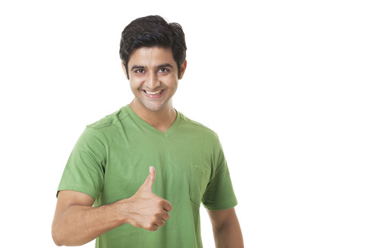 Portrait of happy young man giving you thumbs up on white background 