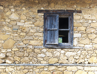 Wall of an old stone house with a wooden window