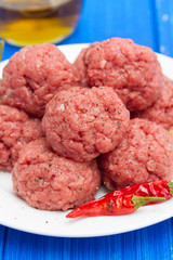 raw meatballs on dish on wooden background