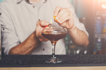 Young bartender making flaming cocktail
