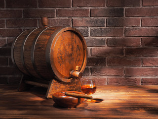 Glass of cognac with barrel on wooden table
