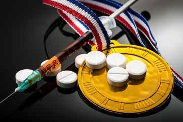 Doping in sports and steroid abuse concept with a gold medal, prescription pills and a syringe on a dark background - obrazy, fototapety, plakaty